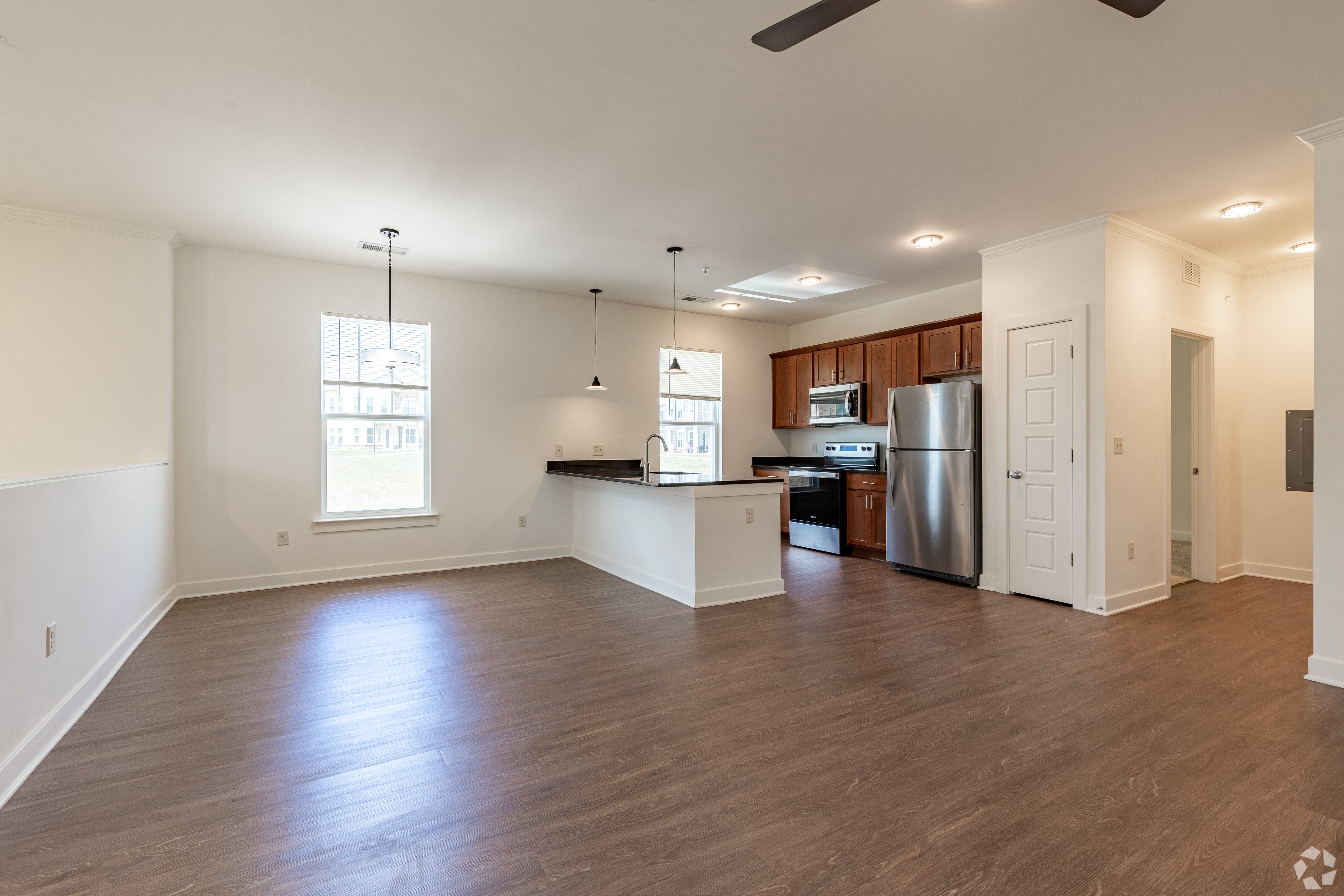an empty living room and kitchen with wood flooring and